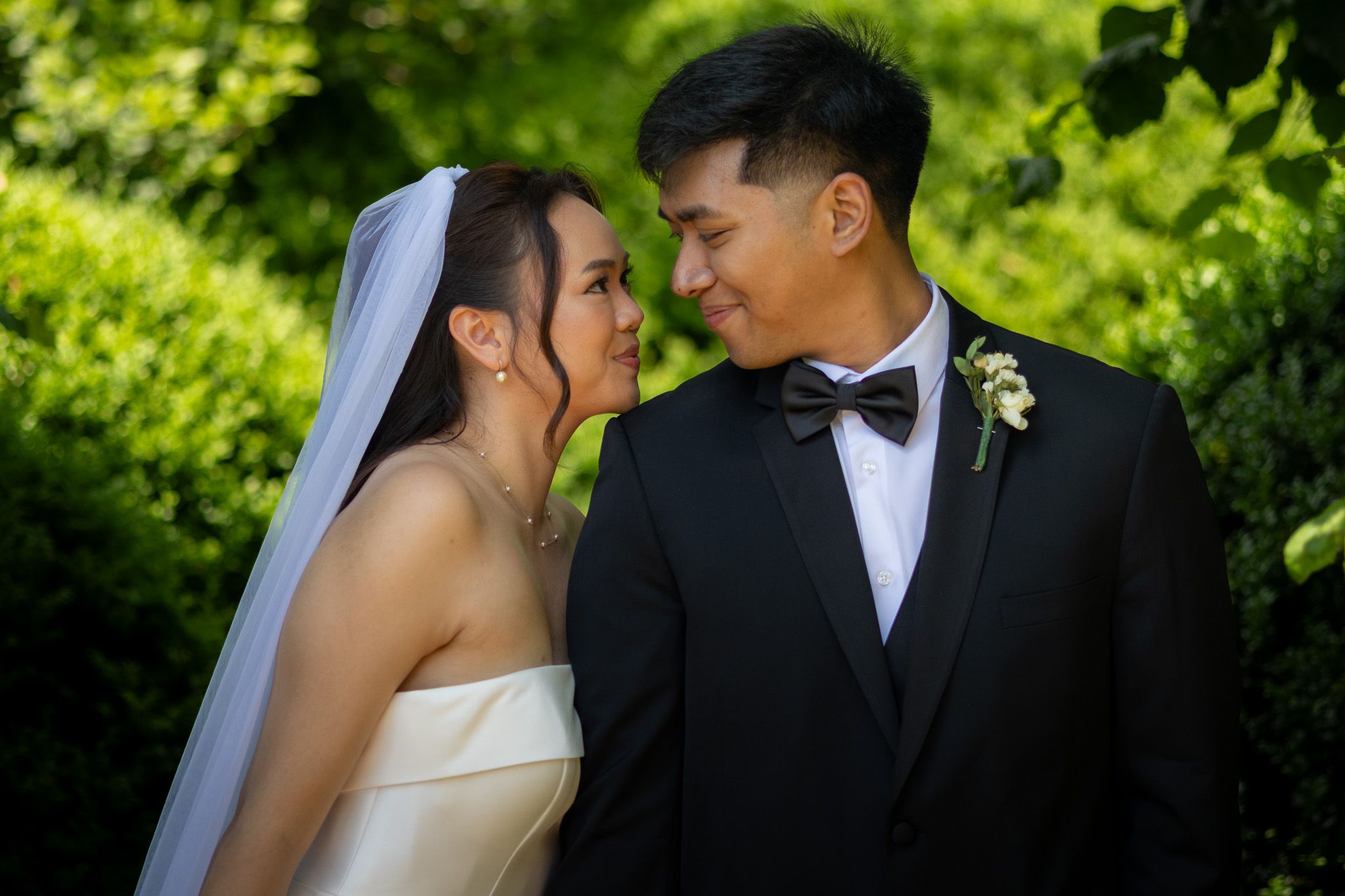 Bride and groom touching foreheads in a garden on their wedding day